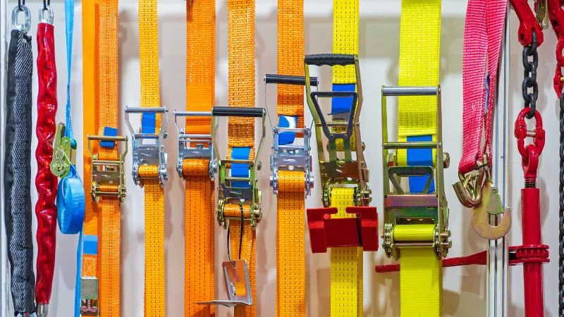 Various colorful ratchet straps and tie-downs displayed on a wall.