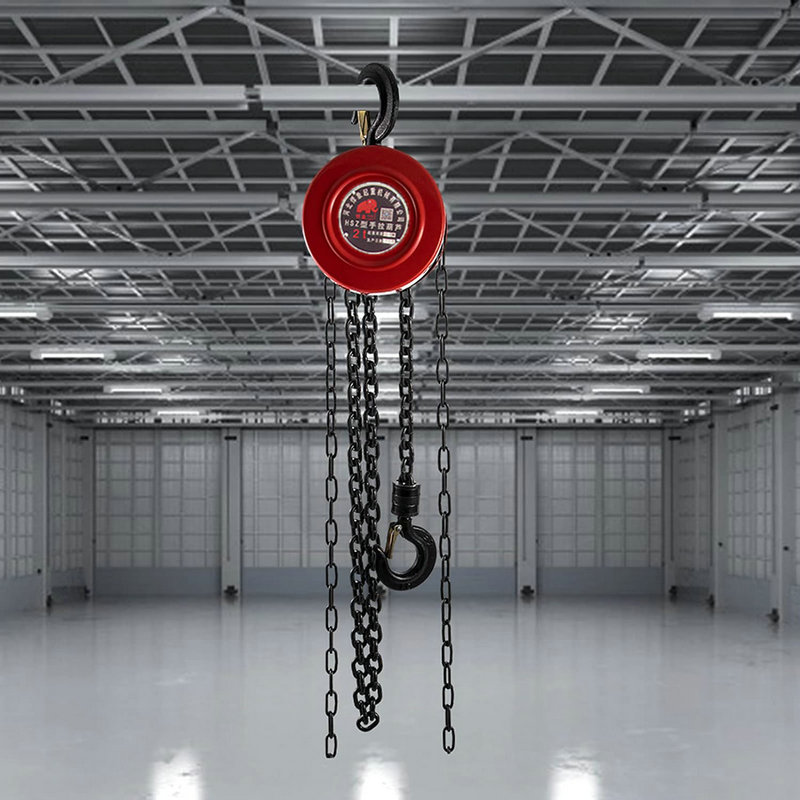 A red manual lift hoist hangs in a spacious industrial warehouse with a high ceiling.