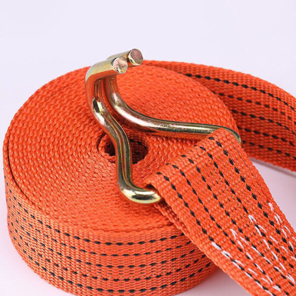 An orange ratchet tie-down strap with black stitching and a metal J hook lies on a white surface.