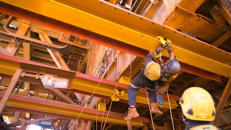 workers using beam clamps in construction