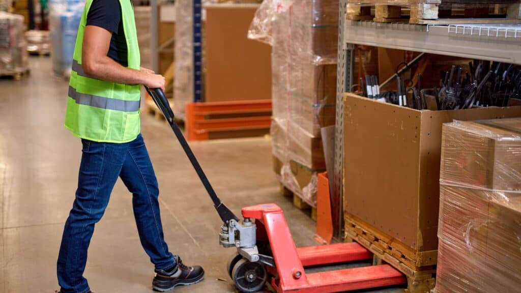 a worker operating pallet truck in a warehouse